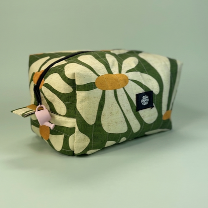 A fabric cosmetic pouch with a green and cream floral pattern, featuring a black zipper, a light pink pull tab, and a black brand label that reads 'STRAIGHT FORWARD'.